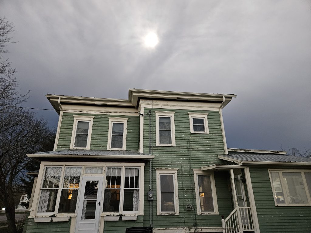 Photo of totality approaching as a dark band coming from the west. It almost appears as though the clouds have formed a hand that is reaching out to grab the sun.